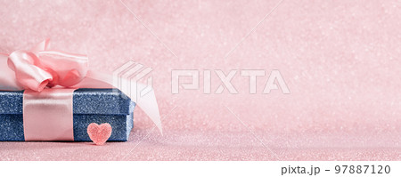 Red heart. Blue sparkling gift box with pink ribbon bow on pink bokeh background. Gift or holiday concept. Mothers Fathers Day, birthday wedding or St Valentines day wide banner copy space. Red heart. Blue sparkling gift box with pink ribbon bow on pink bokeh background. Gift or holiday concept. Mothers Fathers Day, birthday wedding or St Valentines day wide banner copy space. 97887120