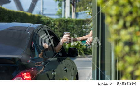 Hand Man in car receiving coffee in drive thru fast food restaurant. 97888894