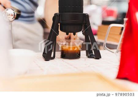 Barista making espresso coffee trought aeropress in cafe. Barista making espresso coffee trought aeropress in cafe. 97890503