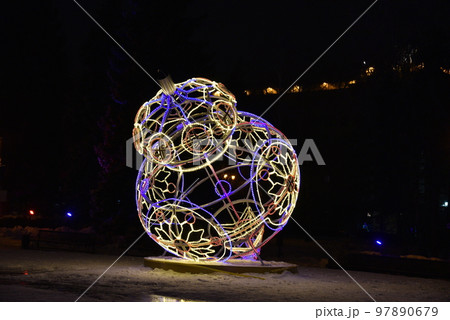 Sculptures with lighting in the form of Christmas tree toys in the park at night. Beautiful giant Christmas tree toys with lights in the city. Sculptures with illumination. 97890679