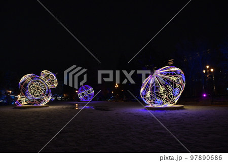 Sculptures with lighting in the form of Christmas tree toys in the park at night. Beautiful giant Christmas tree toys with lights in the city. Sculptures with illumination. 97890686