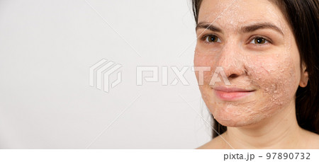 A young brunette woman makes cleansing facial treatments - a mask or scrub to cleanse and nourish the skin, banner with place for text. A young brunette woman makes cleansing facial treatments - a mask or scrub to cleanse and nourish the skin, banner with place for text. 97890732