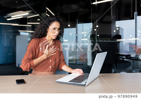 Anxious and scared business woman working inside office, Hispanic woman panic attack and breathing problem, female worker with laptop working. Anxious and scared business woman working inside office, Hispanic woman panic attack and breathing problem, female worker with laptop working. 97890949