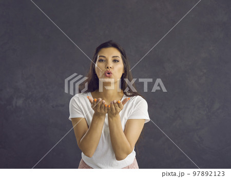 Beautiful friendly woman sends an air kiss to the camera showing her good feelings. Beautiful friendly woman sends an air kiss to the camera showing her good feelings. 97892123