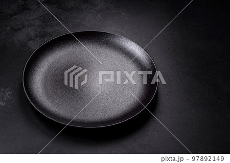 Empty beautiful black ceramic plate on a dark concrete background Empty beautiful black ceramic plate on a dark concrete background 97892149
