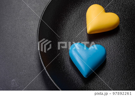 Chocolate hearts in the colors of the Ukrainian flag on a black ceramic plate Chocolate hearts in the colors of the Ukrainian flag on a black ceramic plate 97892261