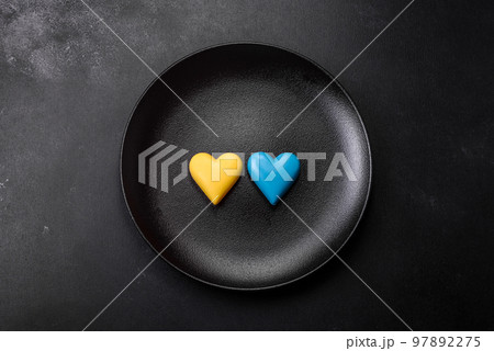 Chocolate hearts in the colors of the Ukrainian flag on a black ceramic plate 97892275