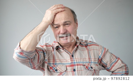 Senior hispanic man trying to remember something or having terrible headache. 97892812