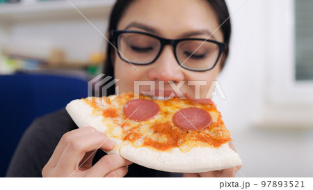 Young woman eats a pizza from delivery service while at work 97893521