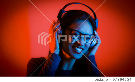Young Asian woman listens to music - strong colorful shot 97894254