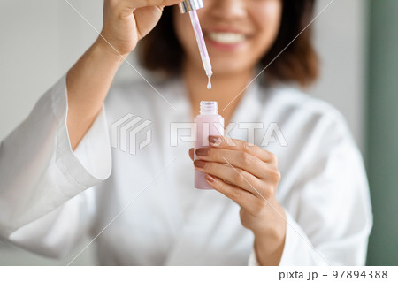 Cropped of young woman using face serum at home 97894388