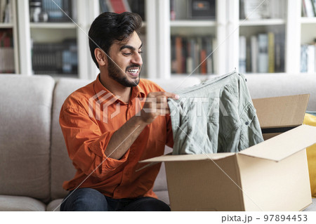 Excited middle eastern man customer receive good parcel, home interior 97894453