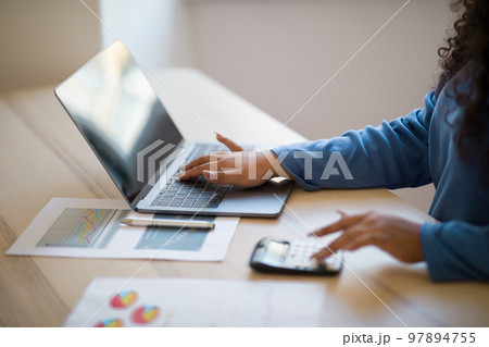 Close up focus on female hands making calculations on laptop 97894755
