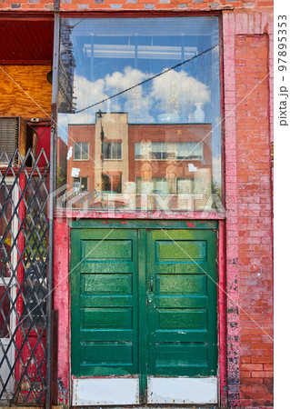 Alley large double green doors with glass display above along red brick wall Alley large double green doors with glass display above along red brick wall 97895353