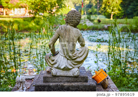 A peaceful lily pond with Tibetan Mongolian Buddhist stone statue overlooking A peaceful lily pond with Tibetan Mongolian Buddhist stone statue overlooking 97895619