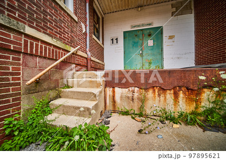 Abandoned building back shipping receiving entrance with brick, rust, and cement steps Abandoned building back shipping receiving entrance with brick, rust, and cement steps 97895621
