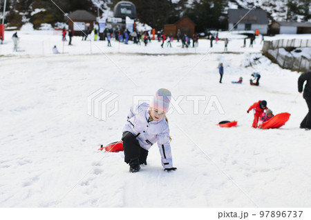 A girl with snow bob sledding in the snow 97896737