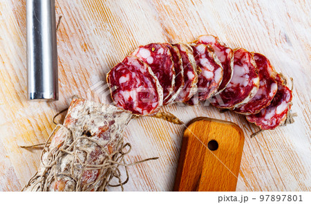 Piacenza salami cut in slices on a wooden surface, close-up Piacenza salami cut in slices on a wooden surface, close-up 97897801
