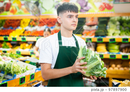 Supermarket male employee lays out cauliflower on shelves in greengrocery store Supermarket male employee lays out cauliflower on shelves in greengrocery store 97897900