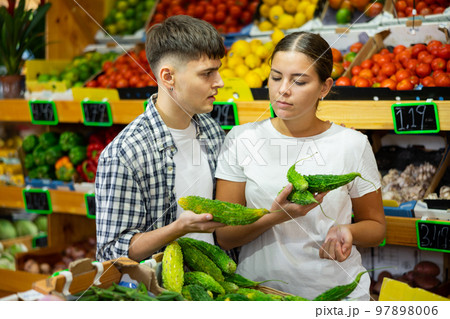 Serious young couple selecting fresh Green Karela at hypermarket 97898006