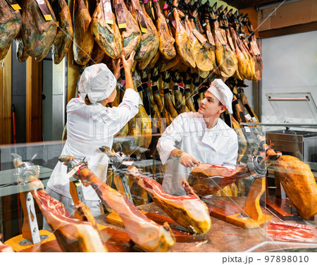 Young woman and man selling ham in jamoneria 97898010