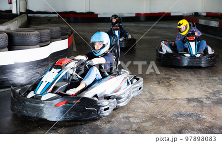 Group of people driving go-carts at racing track Group of people driving go-carts at racing track 97898083