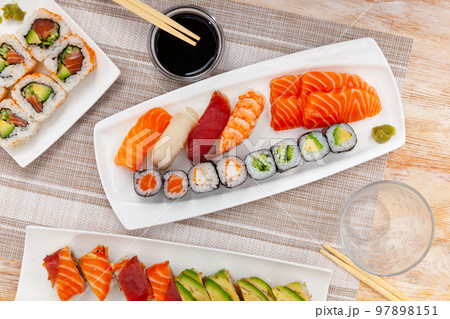 Assorted sushi rolls on plates on tabl 97898151
