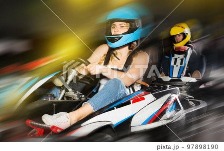 active woman in helmet driving car for karting with other people active woman in helmet driving car for karting with other people 97898190