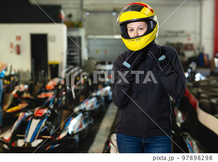 Girl in helmet posing near kart at track 97898298
