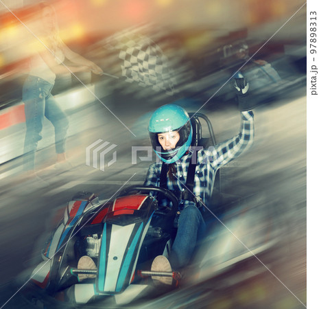 Glad female go-cart racer crossing finish line Glad female go-cart racer crossing finish line 97898313