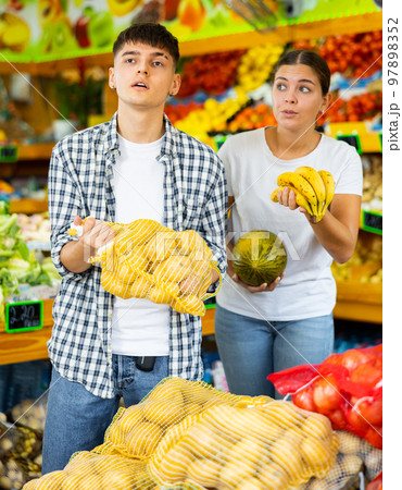 Young husband and wife choose fresh fruit together in grocery supermarket Young husband and wife choose fresh fruit together in grocery supermarket 97898352