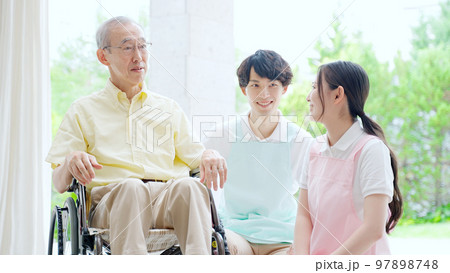 車椅子に乗った高齢者を介護するヘルパー 車椅子に乗った高齢者を介護するヘルパー 97898748