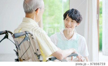 車椅子に乗った高齢者を介護する男性ヘルパー 車椅子に乗った高齢者を介護する男性ヘルパー 97898759