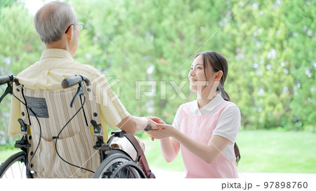 車椅子に乗った高齢者を介護する女性ヘルパー 車椅子に乗った高齢者を介護する女性ヘルパー 97898760