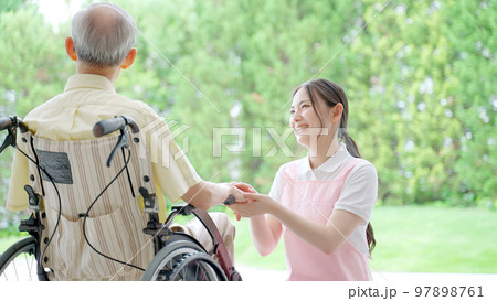車椅子に乗った高齢者を介護する女性ヘルパー 97898761