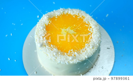 Cake with orange and coconut shavings spinning on a blue background. 97899361