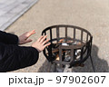 お正月に神社で暖を取る女性 97902607