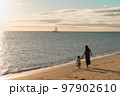 沖縄のビーチで夕日に照らされる親子（母と子） 97902610