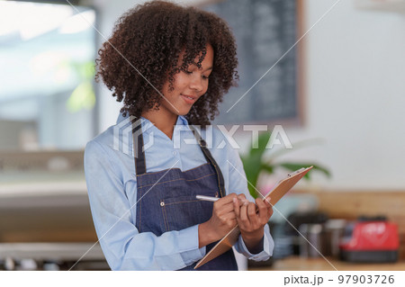 Young Female manager in restaurant with notebook. Woman coffee shop owner with open sign. Small business concept 97903726