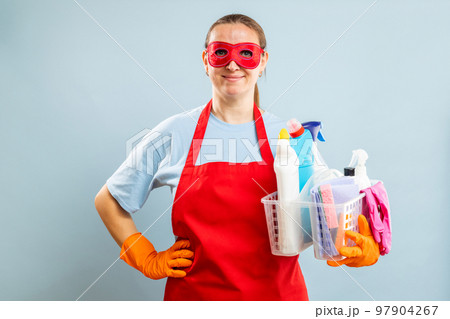 Woman in red mask, gloves and apron holding basket with cleaning supplies Woman in red mask, gloves and apron holding basket with cleaning supplies 97904267