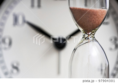 Hourglass and old alarm clock. Sand clock on the background of the dial Hourglass and old alarm clock. Sand clock on the background of the dial 97904301