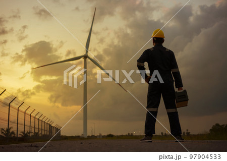 Man inspection engineers preparing and progress check of a wind turbine with safety in wind farm in sunset. Man inspection engineers preparing and progress check of a wind turbine with safety in wind farm in sunset. 97904533