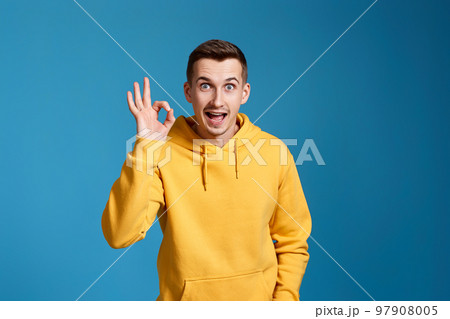 young man in yellow sweatshirt showing Ok gesture 97908005
