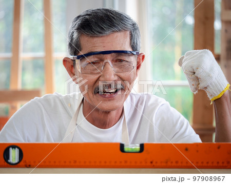 Accuracy and quality. Happy senior carpenter checking the level of a plank of wood. Measurement concept Accuracy and quality. Happy senior carpenter checking the level of a plank of wood. Measurement concept 97908967
