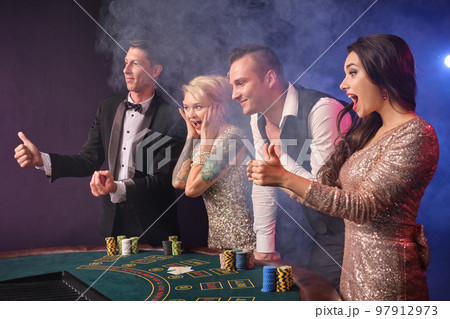 Group of a stylish rich friends are playing poker at casino. 97912973