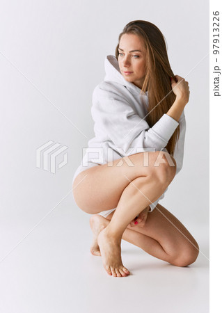 Portrait of beautiful woman posing in white hoodie over grey studio background. Femininity and tenderness Portrait of beautiful woman posing in white hoodie over grey studio background. Femininity and tenderness 97913226