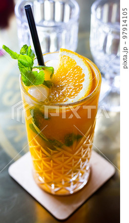 sea buckthorn cocktail with mint in a crystal glass on a table in a bar 97914105