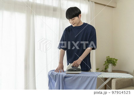 シャツにアイロンをかける若い男性 シャツにアイロンをかける若い男性 97914525