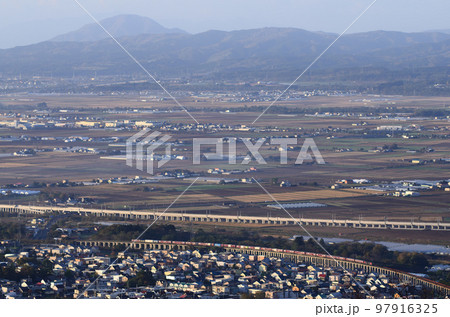 背後に大きく広がる函館平野の縁にある藤城線の高架橋を走る貨物列車 97916325
