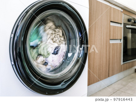 Washing machine with clothes in interior of the laundry room at home. Housework and cleaning concept. 97916443